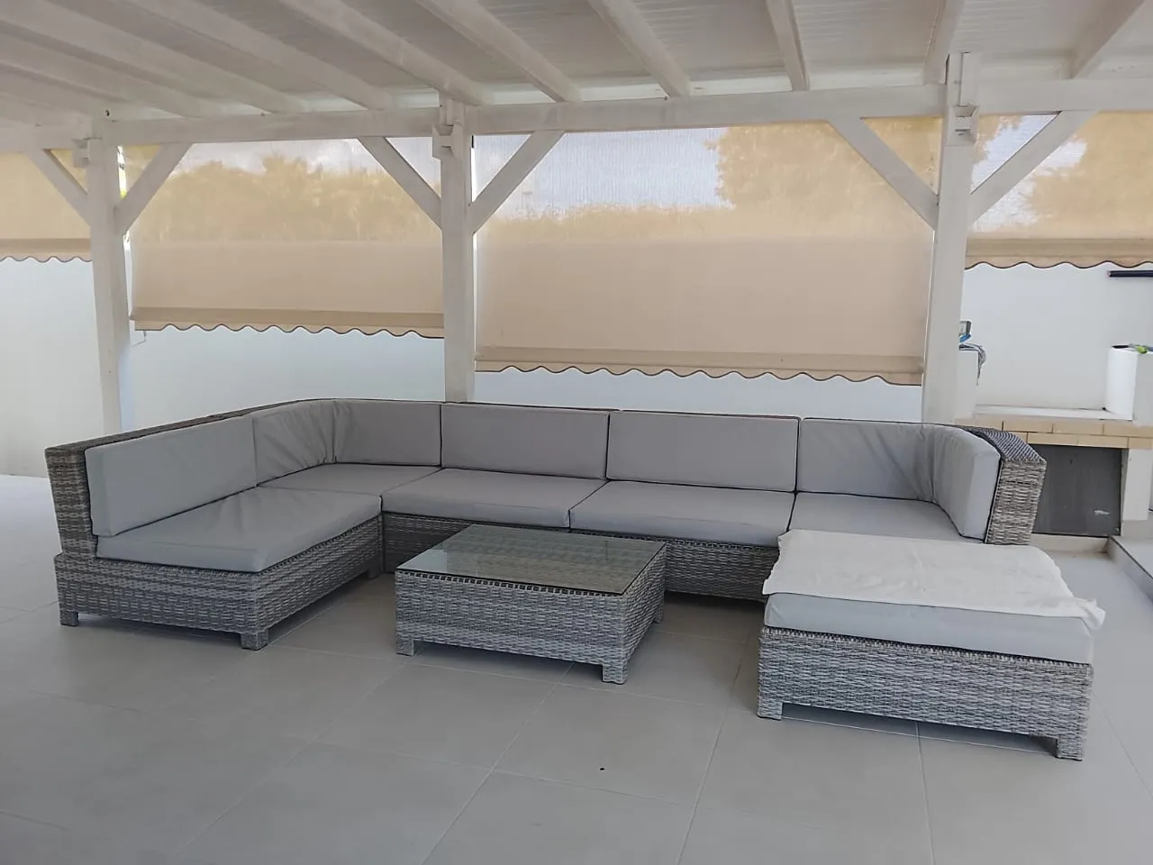 Salon de jardin en résinée tressée équipé de coussins d'extérieur gris confectionnés sur mesure, sous une pergola en Guadeloupe