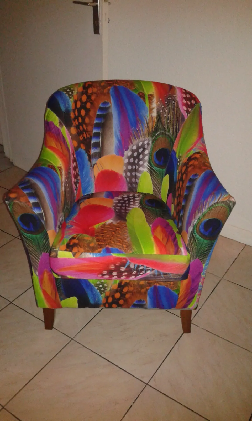 Fauteuil crapaud entièrement réfectionné et recouvert d'un tissu à motif de plumes multicolores, réalisé à l'atelier De Fil en Épingles