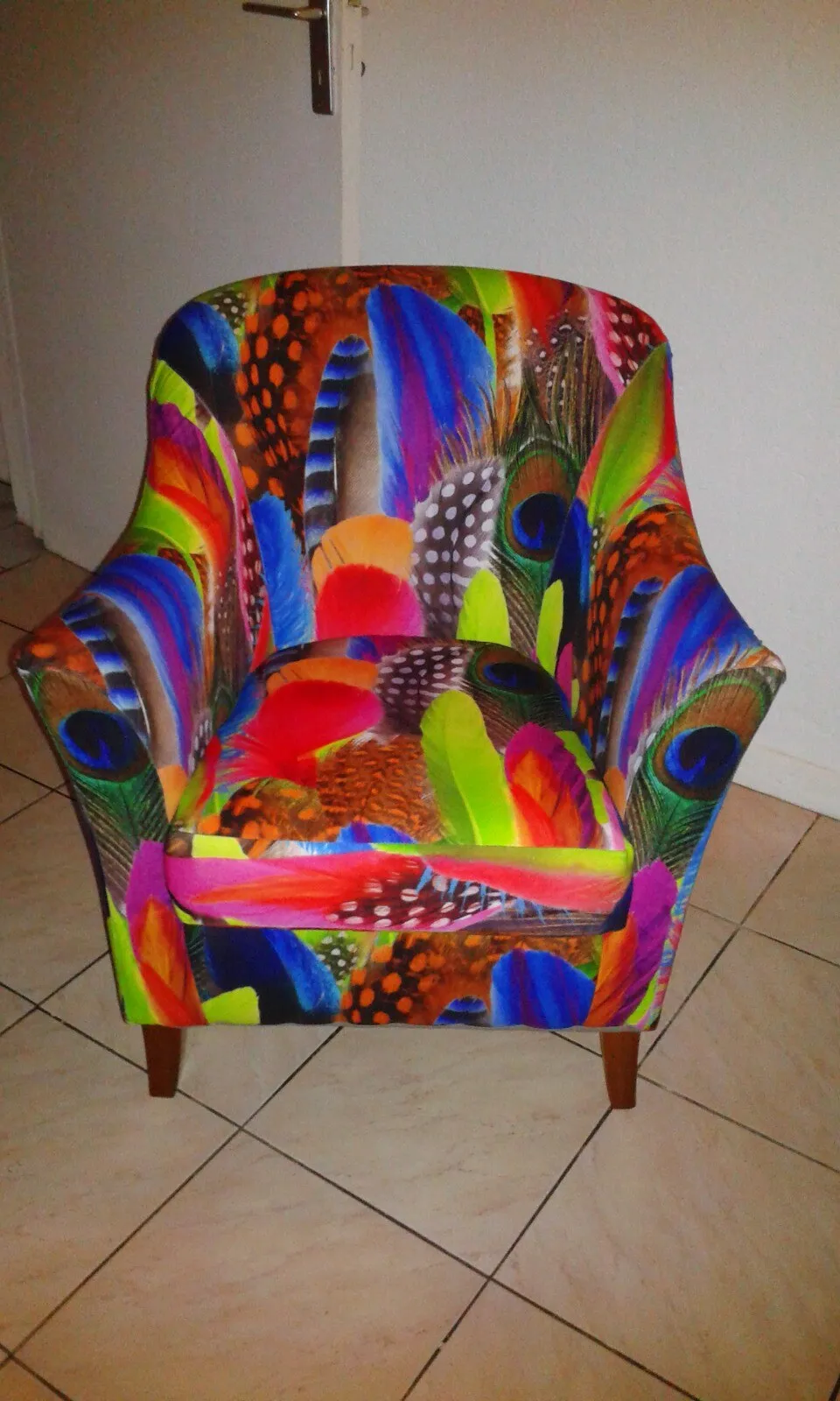 Fauteuil crapaud entièrement réfectionné et recouvert d'un tissu à motif de plumes multicolores, réalisé à l'atelier De Fil en Épingles